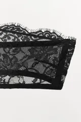 Bralette tipo bandeau negro, confeccionado en encaje suave con diseño floral. Presenta escote recto, hombros descubiertos y cierre de ganchos metálicos en la espalda.