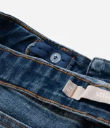 Pantalón de jean corte skinny con cintura media, cierre frontal con botón y cremallera, bolsillos funcionales y detalle de pequeña abertura en el ruedo interno.