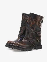 Bota corta de cuero bovino con efecto desgastado en tonos negro y gris. Presenta un diseño robusto con caña arrugada y una cremallera diagonal decorativa con tirador dorado. La suela es gruesa y dentada.
