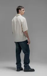 Camisa de manga corta con cuello cubano y cierre frontal de botones, de corte oversize y diseño minimalista.