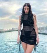 Minivestido negro de microtul transparente con detalles drapeados y tiras ajustables en los laterales.