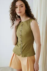 Musculosa turquesa de algodón con escote redondo y cierre frontal decorado con una hilera de múltiples botones vintage variados.