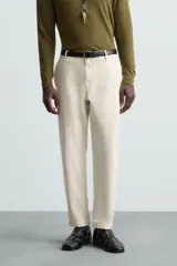 Pantalón chino de algodón color crema, corte regular fit, con cierre frontal de cremallera y botón, bolsillos delanteros y bolsillos traseros de vivo con botón.
