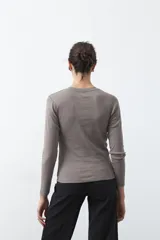 Remera de manga larga color blanco, de calce entallado, con cuello redondo a la base y costuras verticales decorativas que estilizan la silueta.