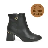 Bota corta de cuero negro con textura granulada, taco cuadrado de altura media con detalle metálico dorado en la parte superior y aplique metálico triangular con strass en el lateral.
