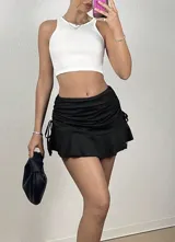 Minifalda negra con volado inferior y ajustable a los lados. Material elastizado y opaco.