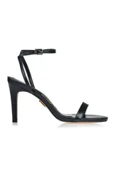 Sandalia de tacón alto color negro, con tira delgada sobre los dedos y pulsera al tobillo con hebilla y detalle de strass.