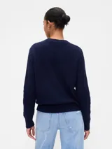 Buzo de algodón color crema con cuello redondo y diseño de punto trenzado en el frente.