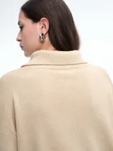 Sweater de punto color verde oliva, con cuello polo abierto en V, manga larga con hombros caídos y terminaciones acanaladas en puños y ruedo.