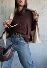 Sweater de tejido de punto color chocolate, con cuello polera, mangas largas con puños acanalados y diseño holgado con aberturas laterales y detalle de botones.