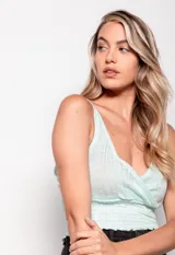 Top tejido color lila, sin mangas, con escote en V profundo y diseño cruzado en frente y espalda. Presenta calados y detalle de punto smock en la parte inferior.