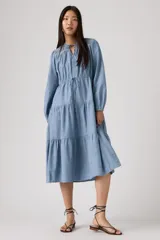 Vestido midi de color azul, con diseño de volados en la falda, mangas largas con puños, escote con cordón ajustable y detalle de bordado en la parte superior.