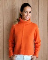 Polerón de lana color naranja, con cuello alto tipo tortuga, diseño holgado y detalle de costura vertical central en el frente.