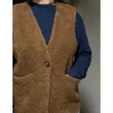 Chaleco de corderito color marrón, de diseño reversible, sin cuello, con cierre de un botón frontal y bolsillos aplicados.