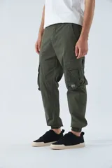 Pantalón cargo color beige, corte slim, con bolsillos laterales con botón, cierre con botón y puños en los tobillos.