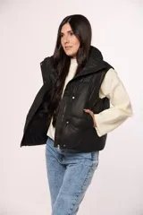 Chaleco tipo puffer de nylon color negro, con cuello alto, cierre frontal y botones a presión.