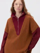 Pullover de tejido acanalado grueso con diseño bicolor en tonos marrón y bordó. Presenta cuello alto con cierre frontal, mangas largas y corte holgado.