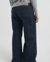 Pantalon de corte recto y tiro medio, confeccionado en tela con estampado de cuadros en tonos azul marino y negro. Presenta cierre frontal con botón metálico, bolsillos laterales y traseros.