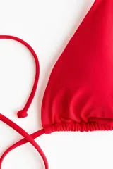 Top de bikini triangular color rojo, con relleno extraíble, tiras ajustables para atar en el cuello y la espalda, y detalle de cuentas en el frente.