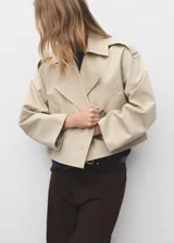 Chaqueta crop de doble botonadura color beige, con cuello pico con solapa, mangas largas y dos bolsillos laterales.