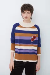 Polera de tejido de punto con diseño de rayas horizontales en tonos beige, marrón, gris y negro. Presenta cuello redondo y mangas largas con puños en contraste.