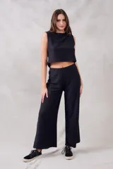 Pantalón negro de corte ancho, tiro alto y textura suave.