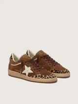 Zapatillas Golden Goose modelo Ball Star, confeccionadas en gamuza marrón con detalles en animal print de leopardo en la puntera y el talón. Presenta la característica estrella lateral en cuero crema, cordones marrones y suela de goma camel.
