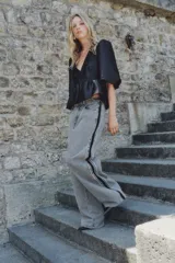 Jean de tiro alto, corte ancho y pierna recta, confeccionado en denim de algodón rígido color gris lavado. Presenta una franja lateral negra contrastante con acabado desflecado en los bordes.