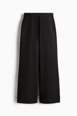 Pantalón deportivo de felpa en color negro, con diseño de pierna levemente acampanada. Presenta cintura elástica con cordón de ajuste y un interior cepillado suave.