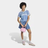 Remera de estilo deportivo inspirada en el fútbol, confeccionada en tejido denim de algodón con efecto lavado. Presenta un diseño de rayas verticales sutiles, cuello polo en color blanco, mangas cortas con bordes en contraste y el logo de la marca estampado en el frente.