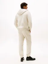 Buzo con capucha y cierre de cremallera, confeccionado en felpa de mezcla de algodón color crema. Tiene dos bolsillos delanteros tipo canguro, puños y bajo de punto canalé.