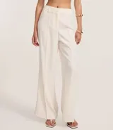 Pantalón flare de tejido plano color blanco, con trabillas en la cintura, cierre tradicional, frisos delanteros y bolsillos falsos atrás.