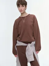 Buzo oversize color marrón, con cuello redondo acanalado, mangas largas anchas con puños elásticos y bajo regulable con elástico.