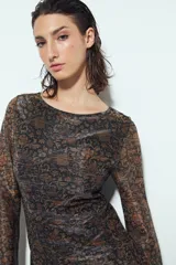 Vestido corto de manga larga, escote redondo y calce ajustado. Confeccionado en tejido liviano con estampado tipo damasco o paisley en tonos negro, marrón y dorado/plateado brillante.