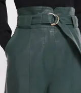 Short clochard negro de cuero sintético con cintura alta, cinturón con hebilla metálica y bolsillos laterales.