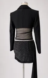 Conjunto de dos piezas compuesto por un blazer corto tipo torera de manga larga y una minifalda ajustada con detalle de strass brillante. La falda presenta un diseño drapeado y la chaqueta tiene un corte estructurado.
