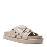 Sandalias planas Miss Carol modelo Nami, color beige, con múltiples tiras cruzadas decoradas con tachas metálicas plateadas y suela tipo plataforma baja.