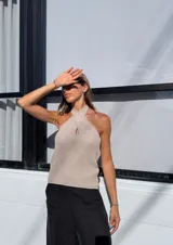Top tejido color beige con lurex, de breteles finos y escote halter cruzado con abertura central.