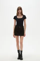 Falda mini de jean color marrón oscuro, con diseño de cinco bolsillos, cierre frontal con botón y costuras a tono.