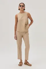 Conjunto color beige compuesto por un top sin mangas y un pantalón chino de lino metalizado, con tiro medio-alto, pierna recta, bolsillos laterales y traseros.