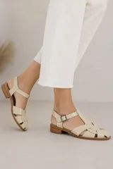 Sandalias de cuero color cobre metalizado, tipo franciscanas, con diseño de tiras cruzadas, puntera cerrada y tira ajustable con hebilla en el tobillo. Cuentan con un pequeño tacón plano.