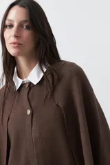 Saco tipo capa de punto color negro, con silueta fluida, corte amplio y cierre frontal con dos botones dorados.