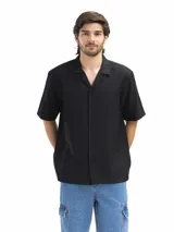 Camisa negra de manga corta, con cuello cubano y corte suelto.