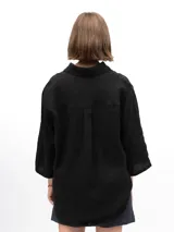 Camisa unisex de lino con mangas tres cuartos, cuello clásico, cierre frontal con botones y un bolsillo aplicado en el pecho.