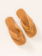 Sandalia plana tipo ojota de cuero vacuno, color negro, con tira ancha y acolchada que pasa entre los dedos.