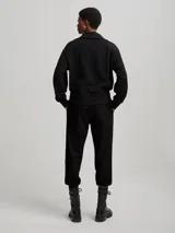 Sweater deportivo negro con cierre de medio largo en el cuello y textura acanalada.