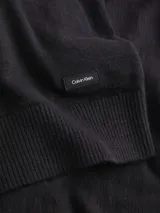 Sweater negro de algodón orgánico con textura rugosa, cuello redondo, hombros caídos y puños y bajo de canalé. Presenta una pequeña etiqueta con logo de goma de Calvin Klein en el bajo.