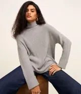 Suéter alargado de punto color rojo, con cuello alto ajustado y mangas largas ajustadas.