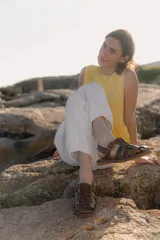 Sandalias de cuero marrón con diseño de tiras entretejidas y hebilla lateral.