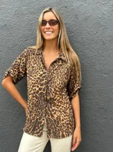 Camisa de manga corta con estampado animal print, cuello clásico y cierre frontal con botones. Presenta un corte holgado y fluido.